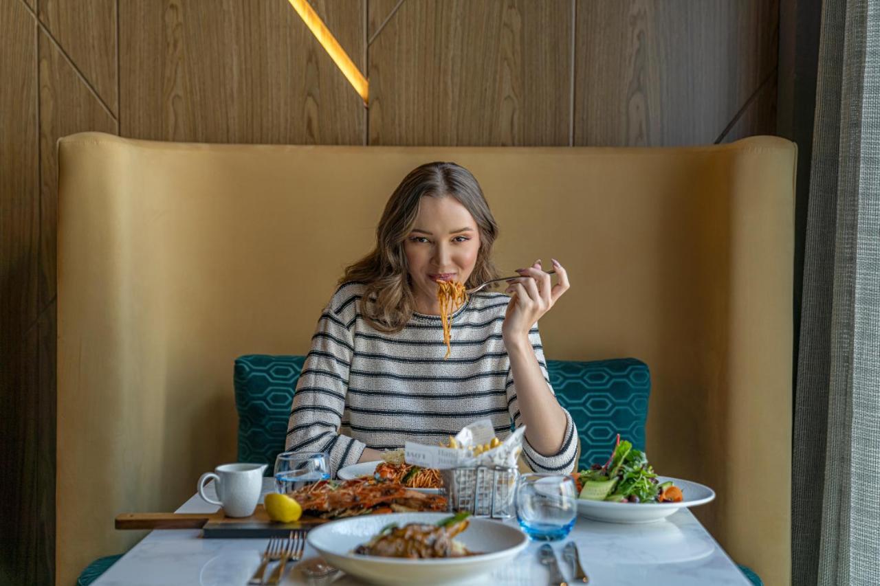 Pullman Sharjah Hotel Bagian luar foto A woman eating at a restaurant